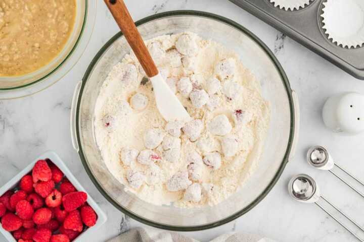 dry muffin ingredients and raspberries in glass bowl
