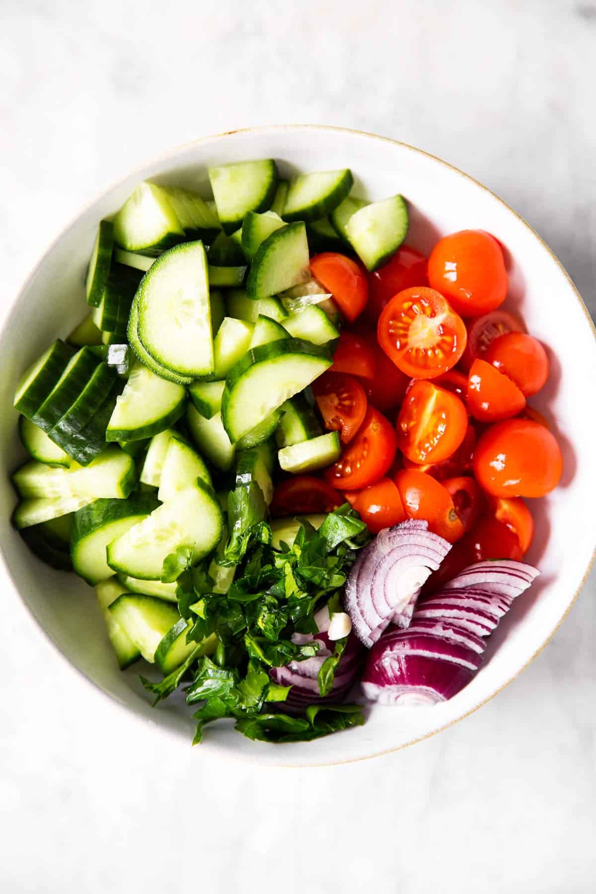 vegetables for tomato cucumber salad in white bowl