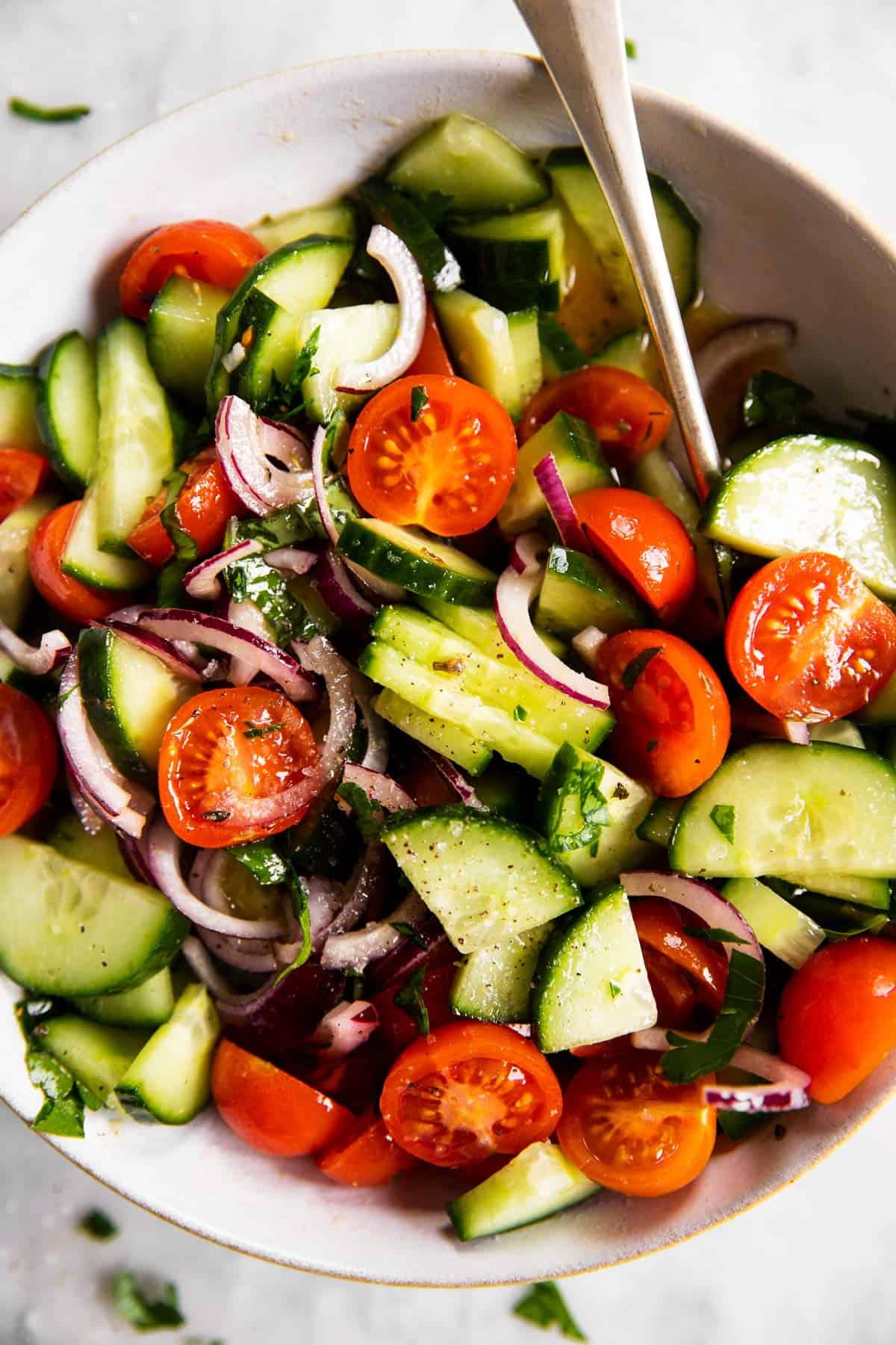 overhead close up view of white bowl with cucumber tomato salad