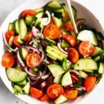 overhead view of white bowl with cucumber tomato salad