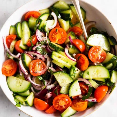 overhead view of white bowl with cucumber tomato salad