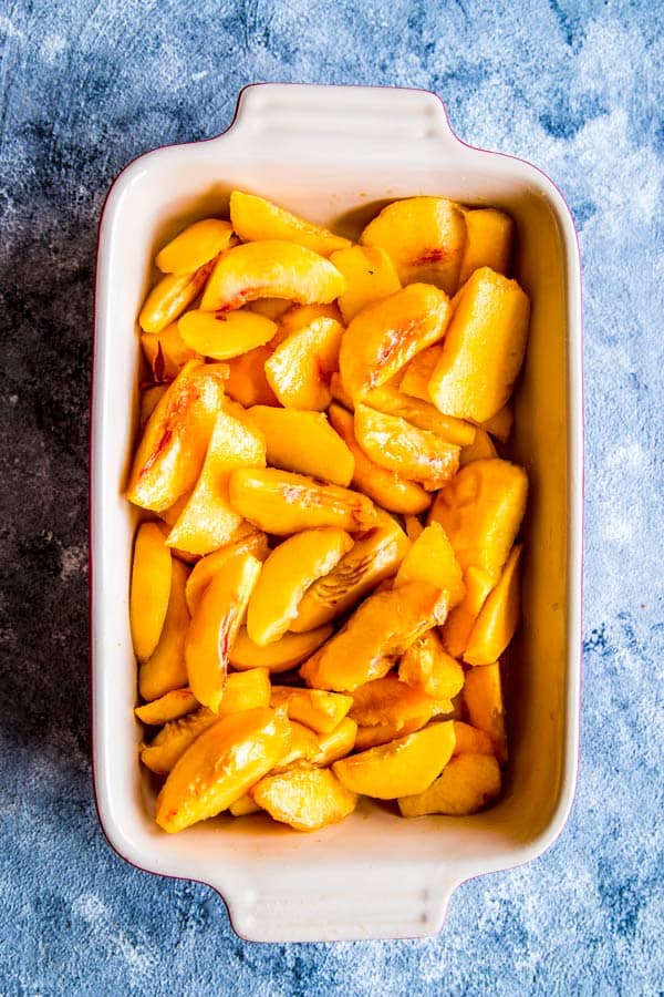 sliced peaches in a casserole dish for peach cobbler