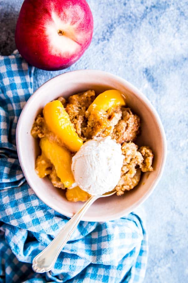 fresh peach cobbler in a bowl with ice cream