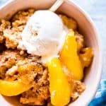 closer photo of a bowl with fresh peach cobbler and ice cream