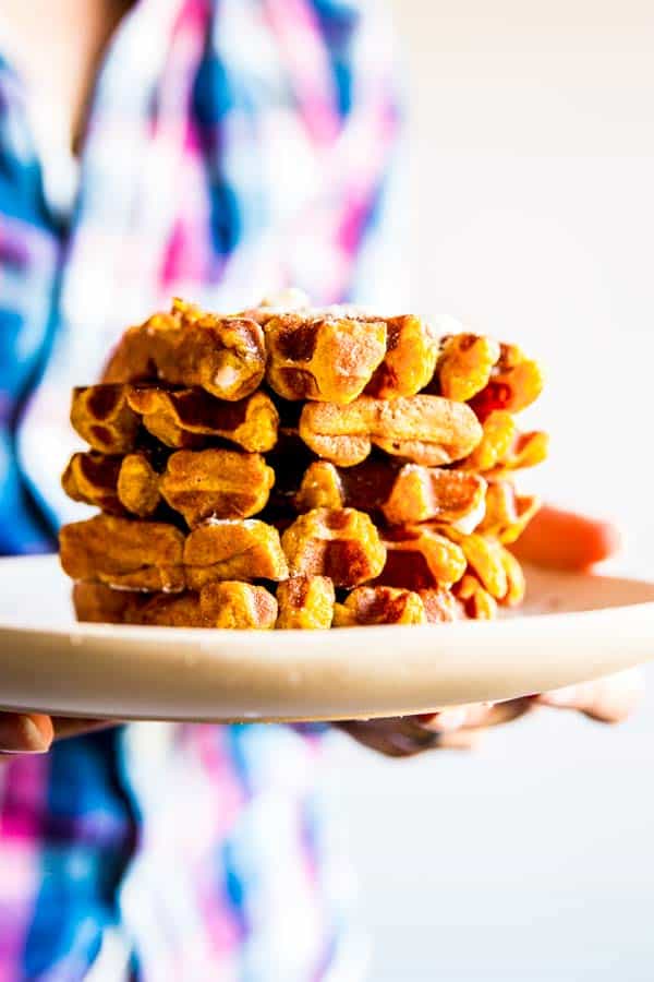 woman holding a stack of pumpkin pancakes