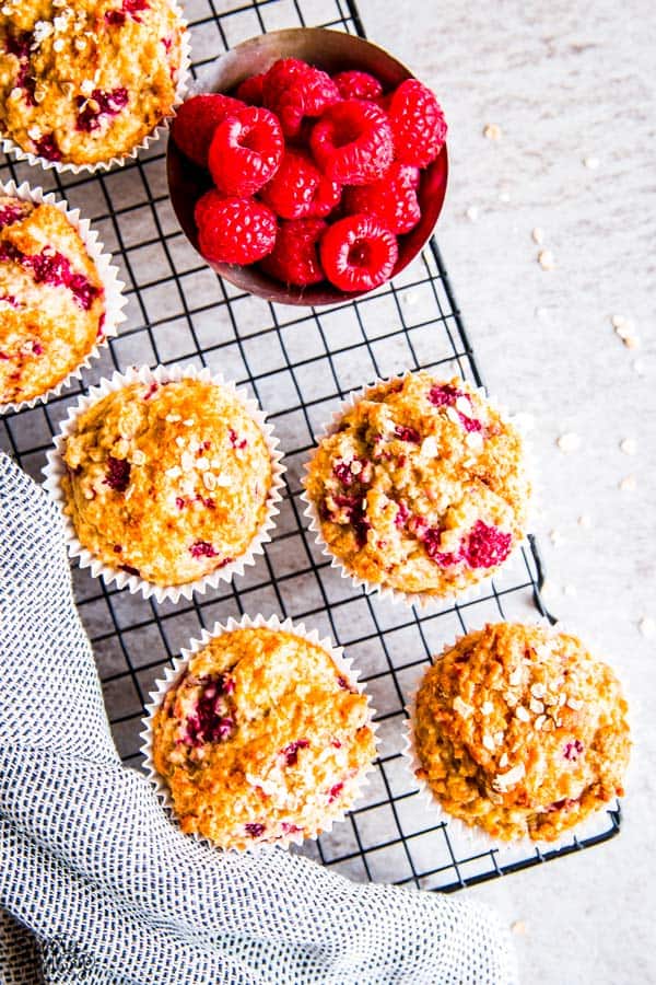 raspberry oatmeal muffins and fresh raspberries on a cooling rack