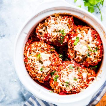 slow cooker stuffed peppers in a white crock with a wooden spoon