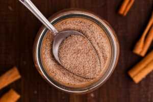 Spooning cinnamon sugar spice mix from a jar.