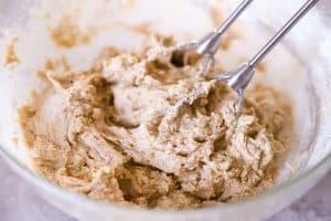 cookie dough in a glass bowl with beaters in it