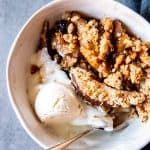 white bowl with pear crisp and a scoop of ice cream
