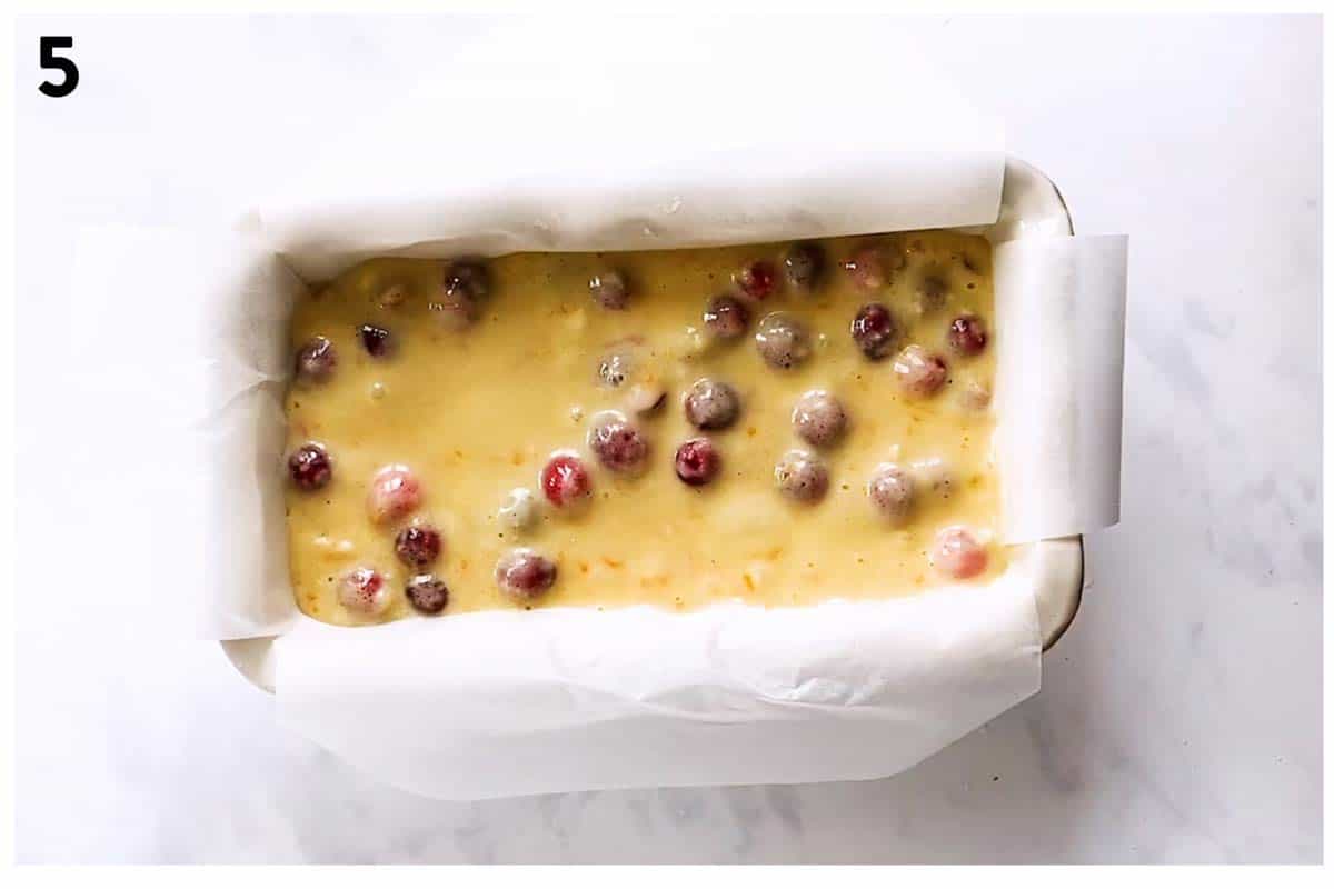 overhead view of lined loaf pan with cranberry bread batter