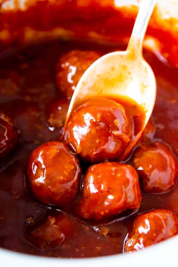 spooning cranberry bbq meatballs from a crockpot