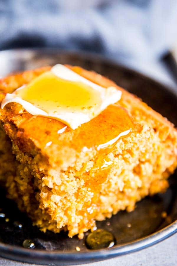 cornbread with honey and butter on a black plate