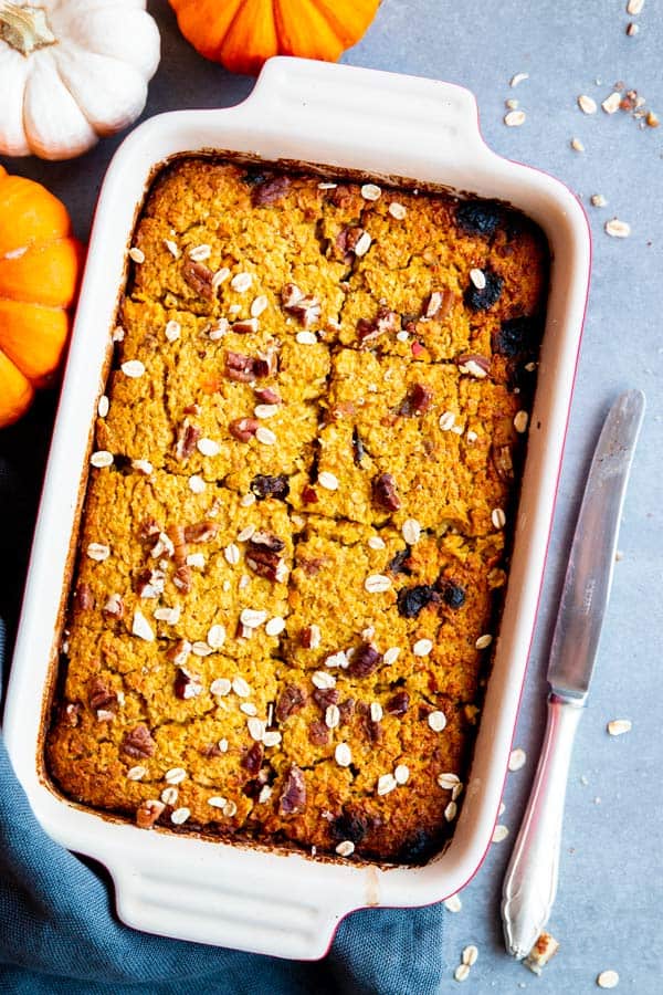 pumpkin baked oatmeal in a baking dish, with pumpkins around it