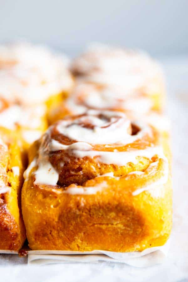 close up photo of pumpkin cinnamon rolls with frosting
