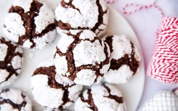 Chocolate crinkle cookies on a plate next to a spool of red and white twine