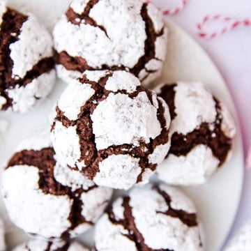 Chocolate crinkle cookies on a plate next to a spool of red and white twine