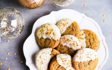 a plate with chewy gingersnap cookies next to Christmas ornaments