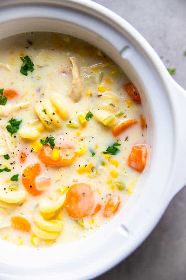 creamy chicken noodle soup in a white crockpot