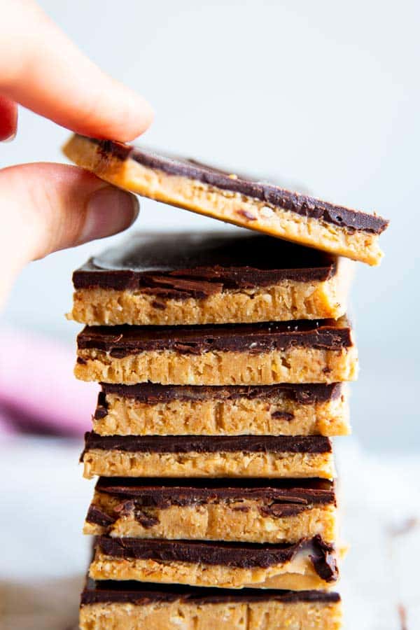 taking a peanut butter bar off a stack of no bake chocolate peanut butter bars