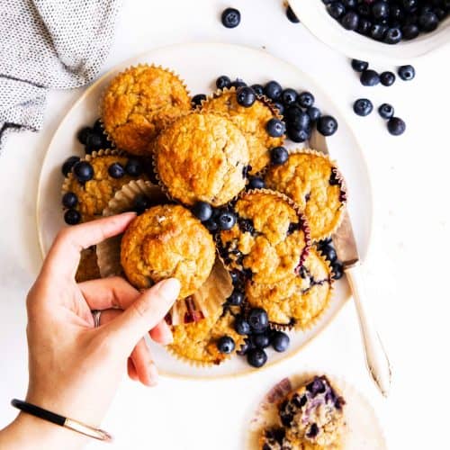 top down view on plate with oatmeal muffins, female hand grabbing one