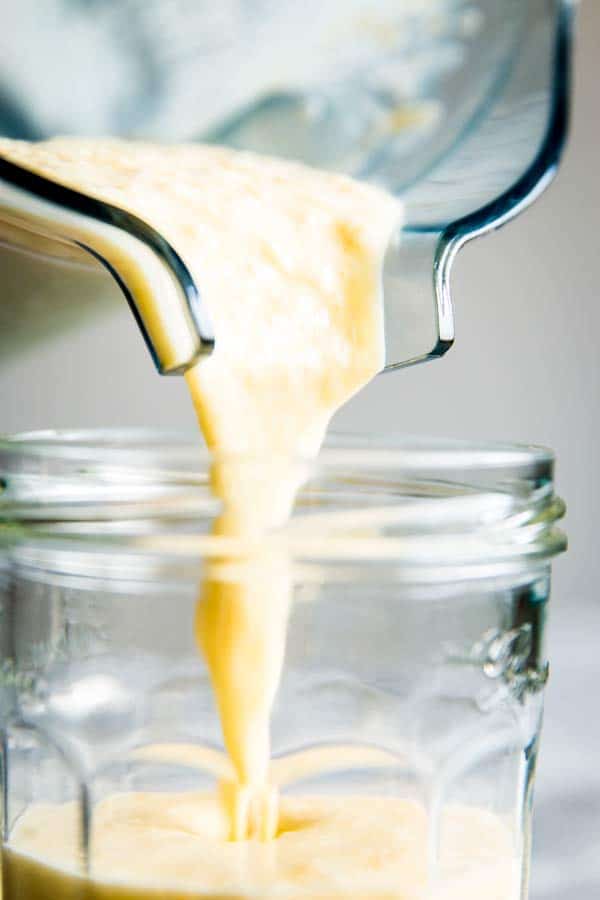 pouring pina colada smoothie into a glass