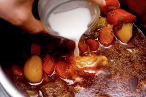 pouring cornstarch slurry into beef stew