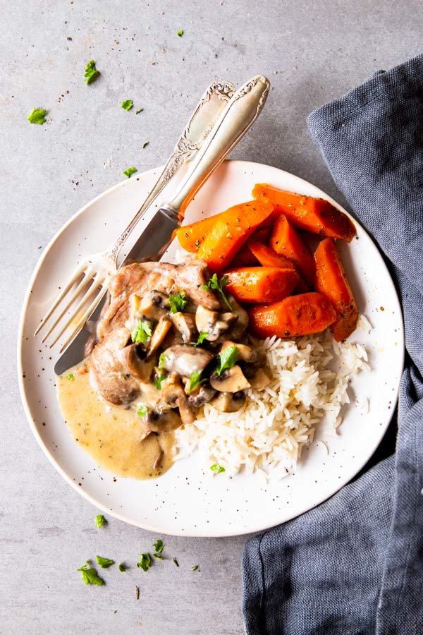 instant pot mushroom pork chops on a plate with rice and carrots