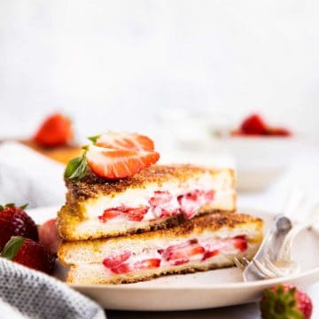 stack of stuffed French toast on a plate with fresh strawberries