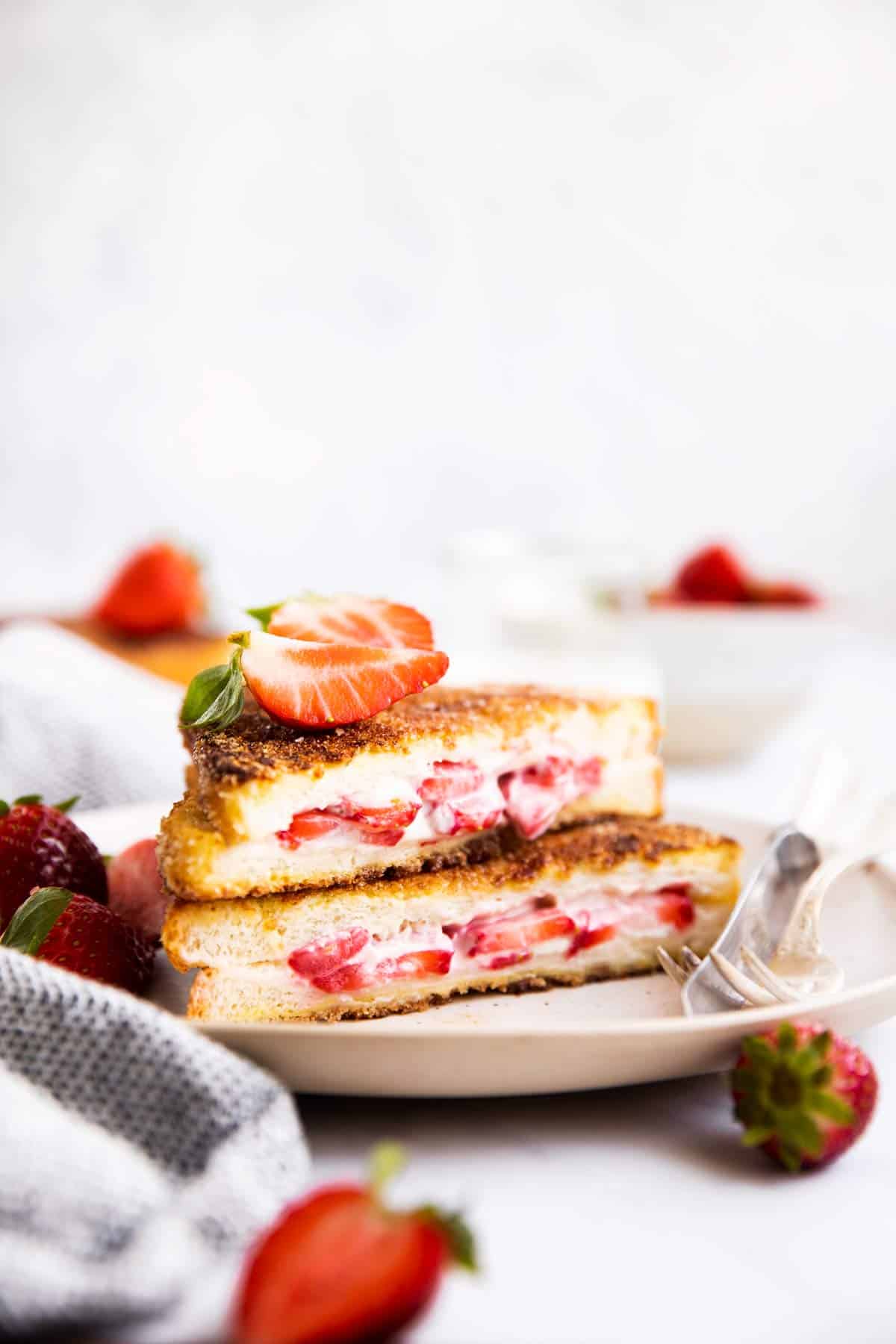 stack of stuffed French toast on a plate with fresh strawberries