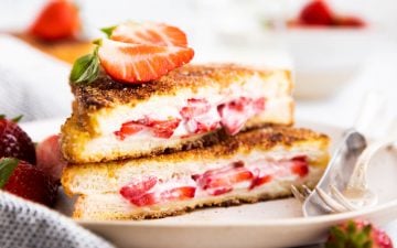 stack of stuffed French toast on a plate with fresh strawberries