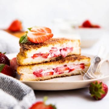 stack of stuffed French toast on a plate with fresh strawberries