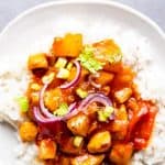 close up photo of a white plate with rice and pineapple chicken