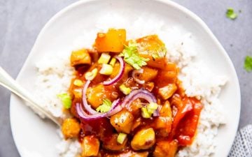 close up photo of a white plate with rice and pineapple chicken