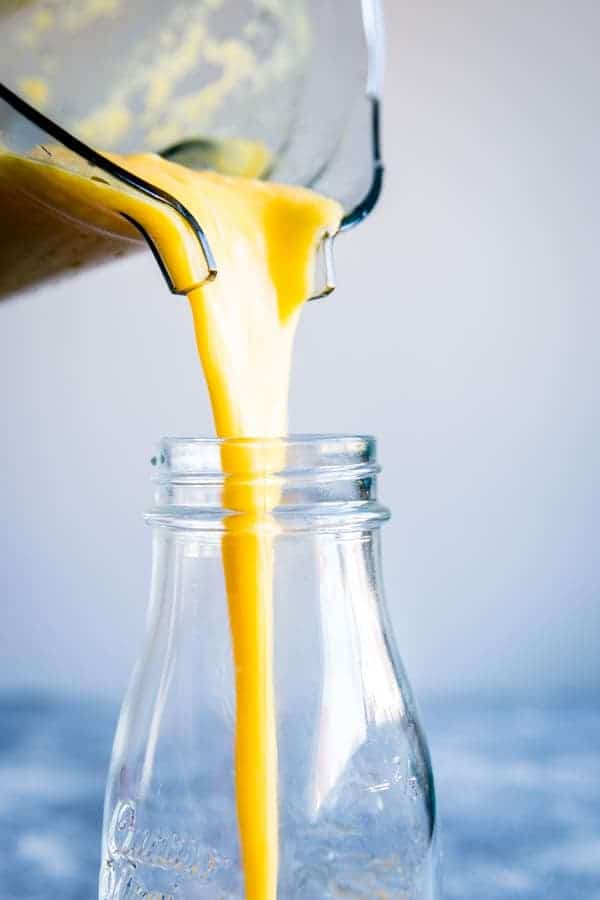 pouring pineapple mango smoothie from a vitamix