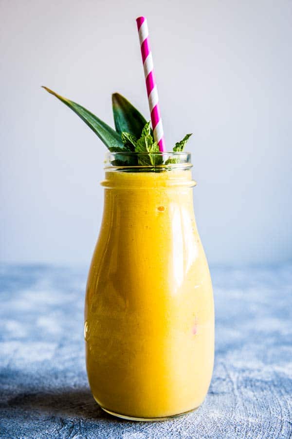 glass bottle filled with pineapple mango smoothie