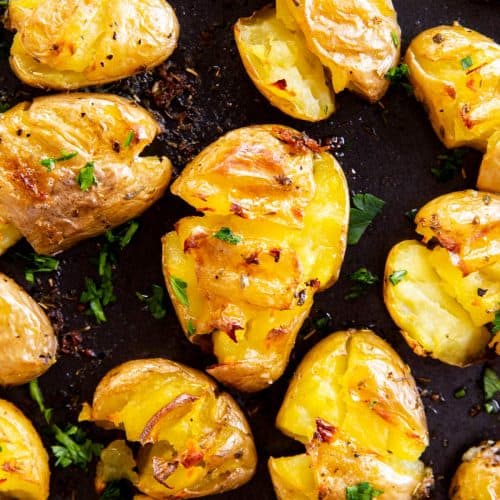 overhead close up view of smashed potatoes on black pan