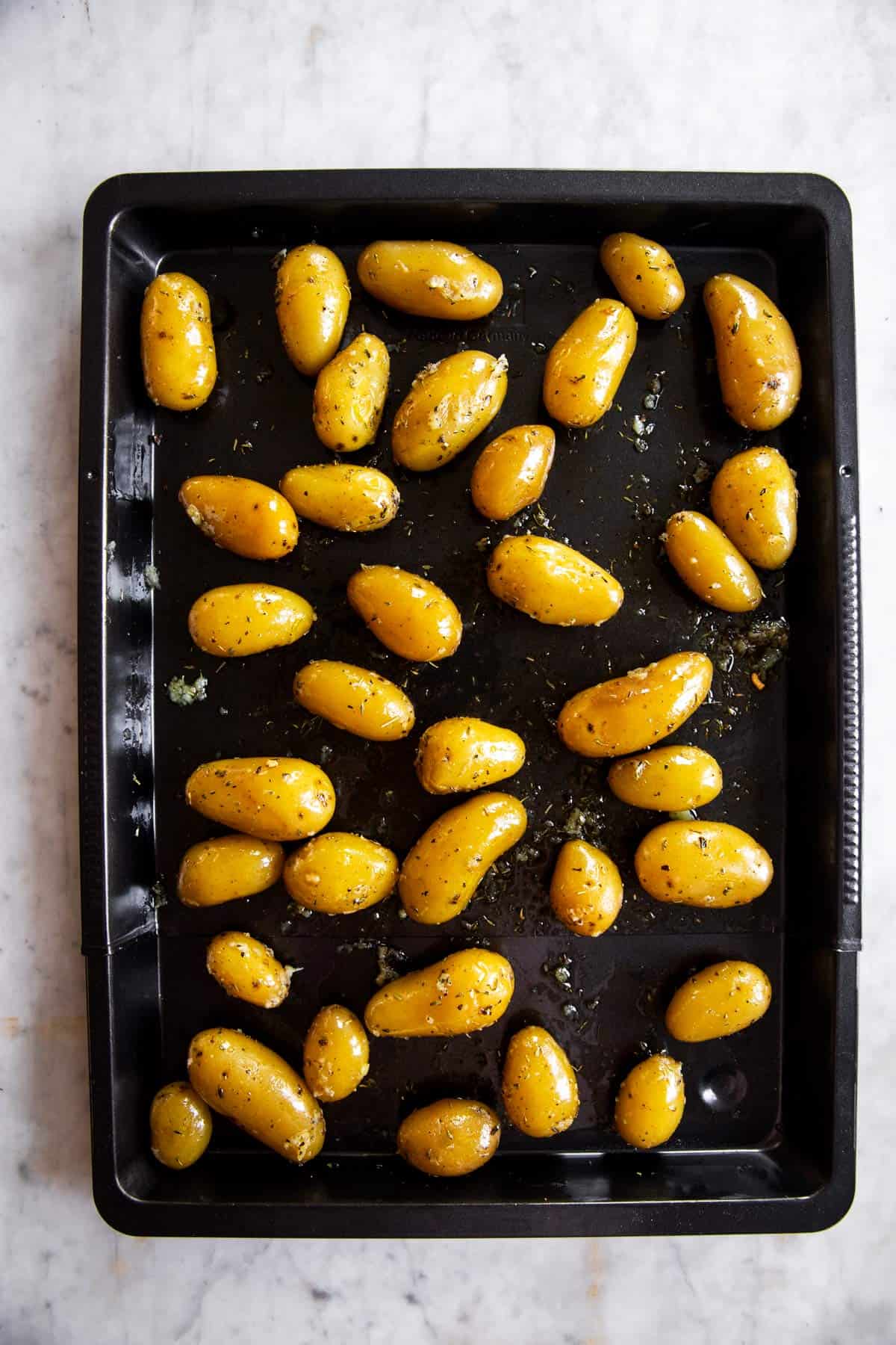 dark baking sheet with seasoned potatoes