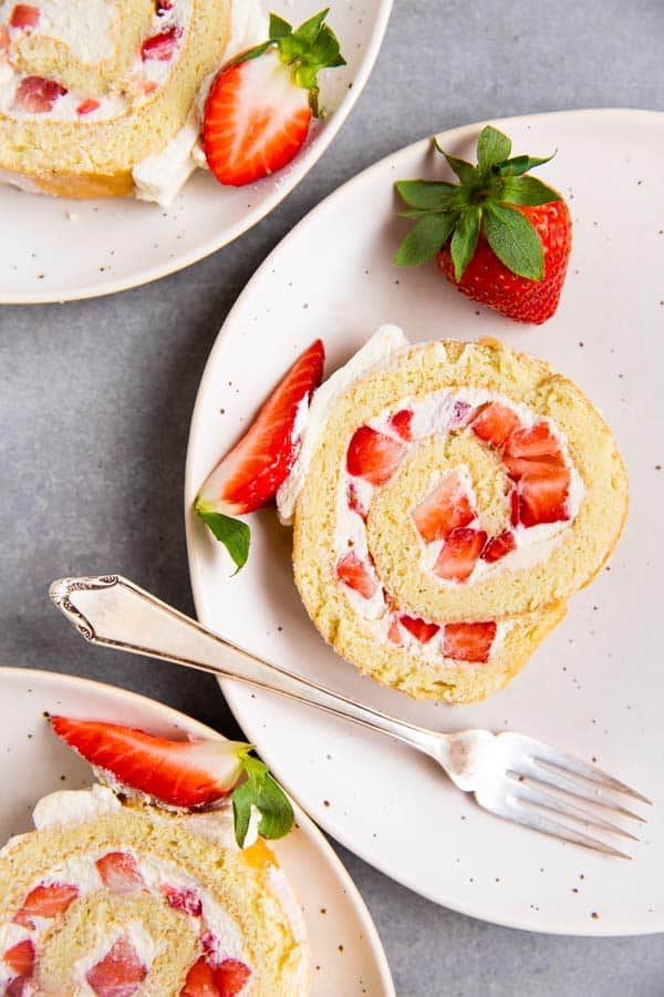 strawberry cake roll slices on white plates