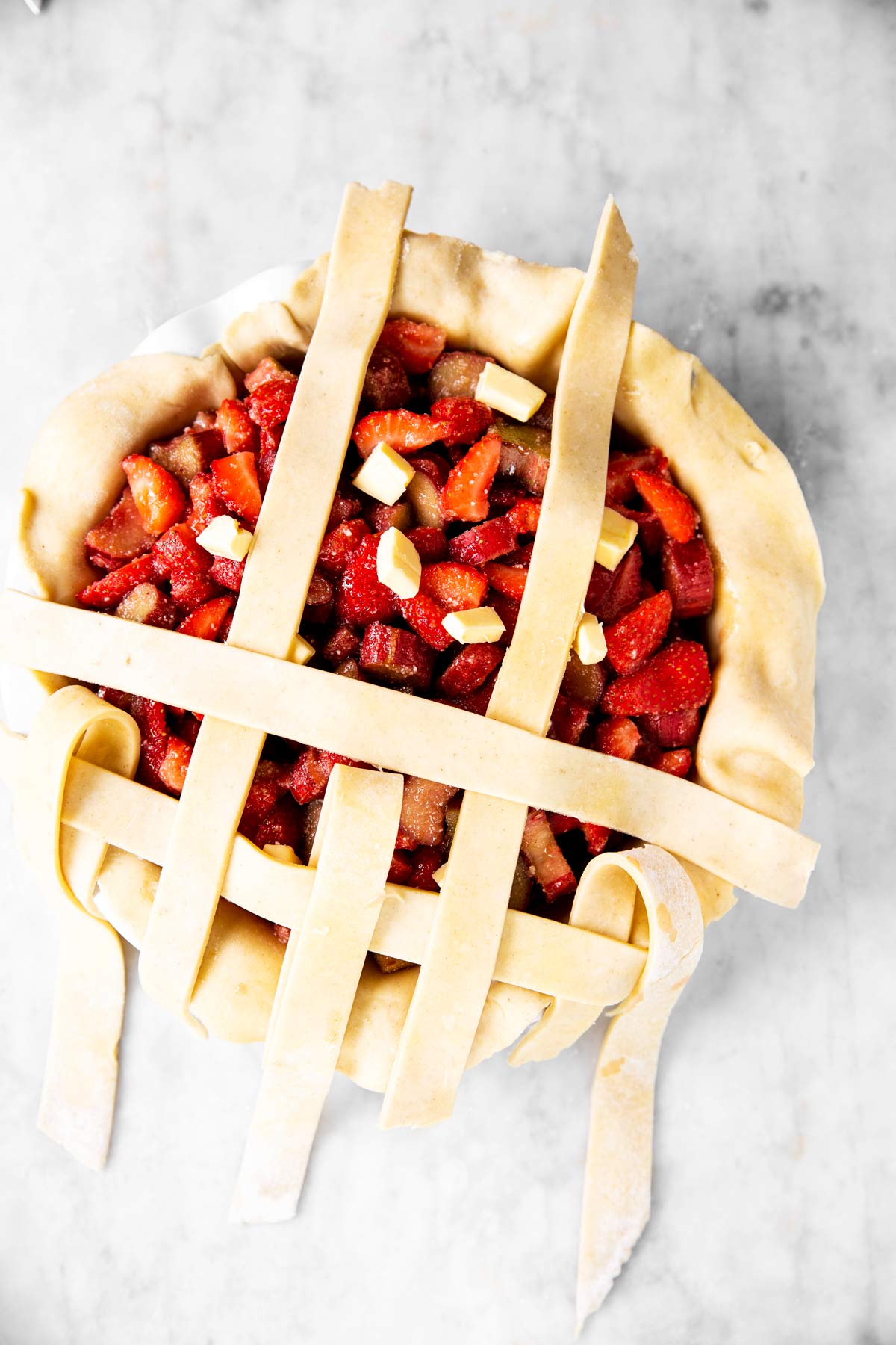 second step of lattice crust weave on top of strawberry rhubarb pie