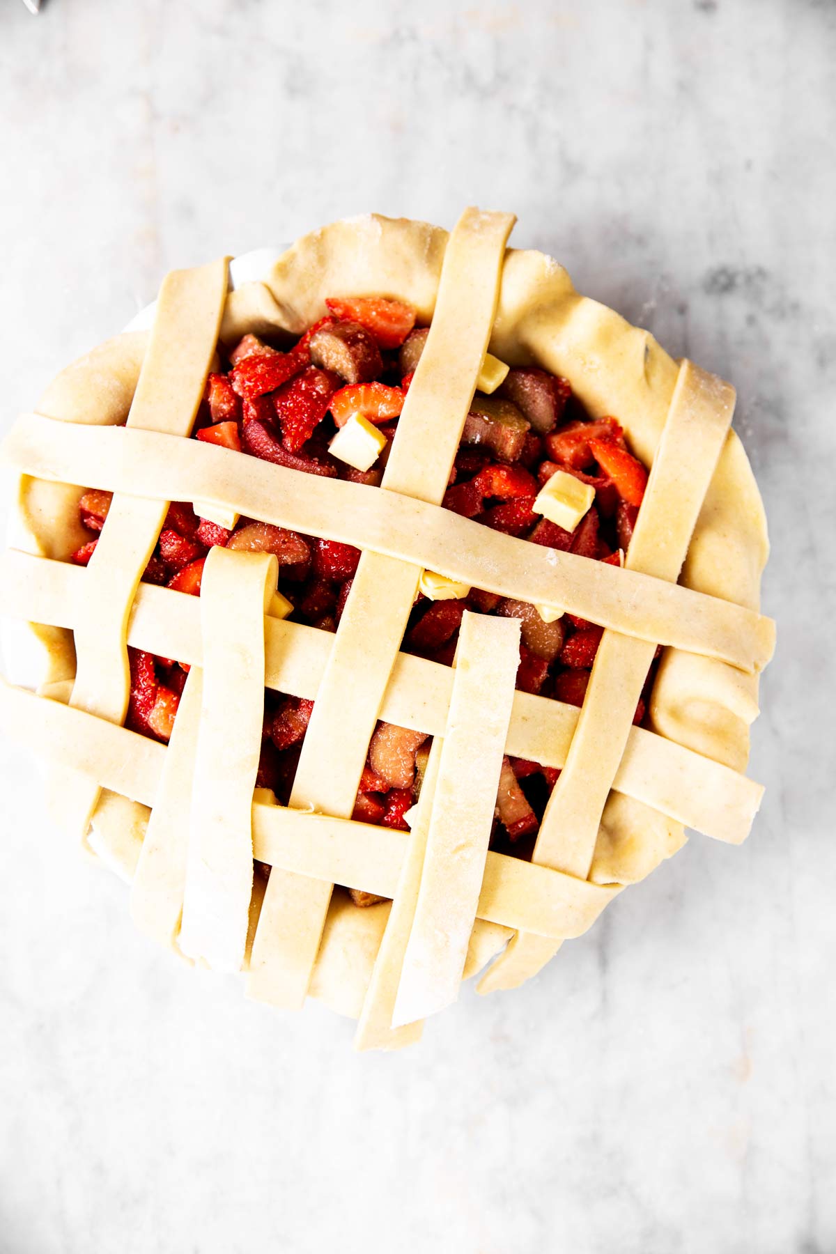 third step of lattice crust weave on top of strawberry rhubarb pie