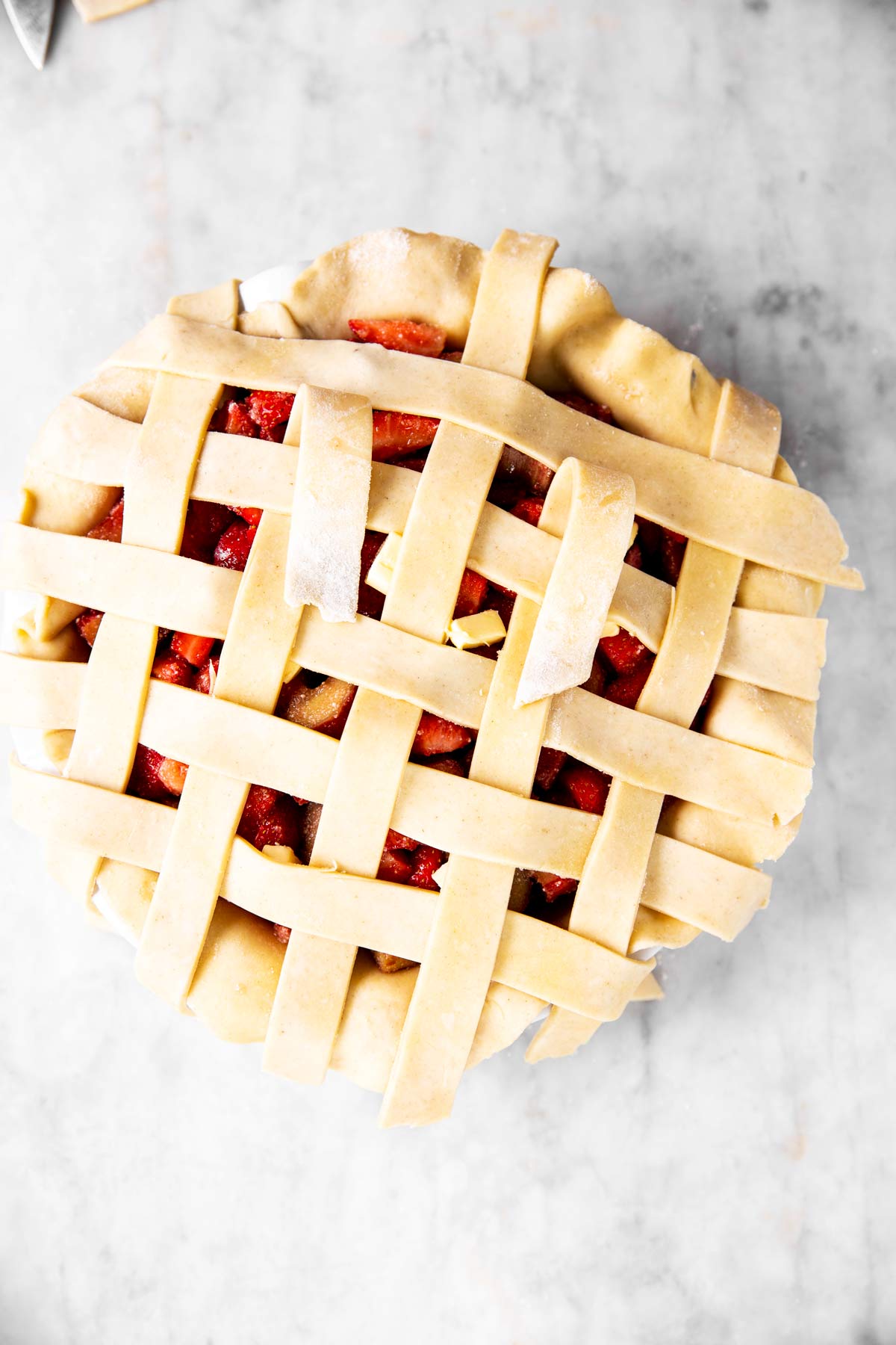 fourth step of lattice crust weave on top of strawberry rhubarb pie