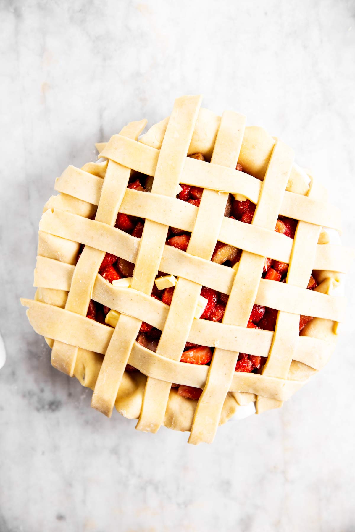 fifth step of lattice crust weave on top of strawberry rhubarb pie