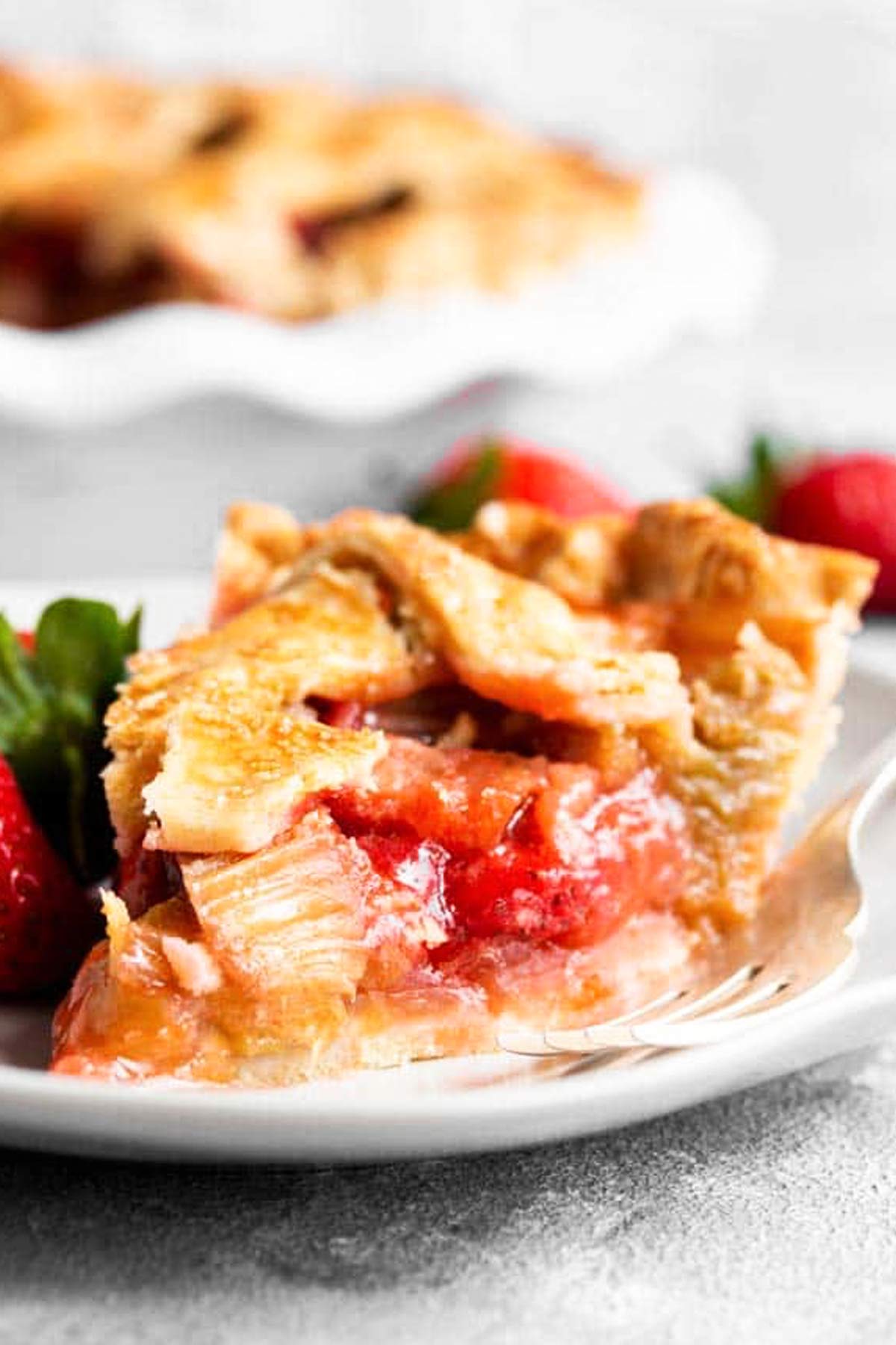slice of strawberry rhubarb pie on white plate