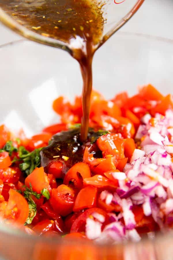 pouring balsamic dressing over bruschetta topping