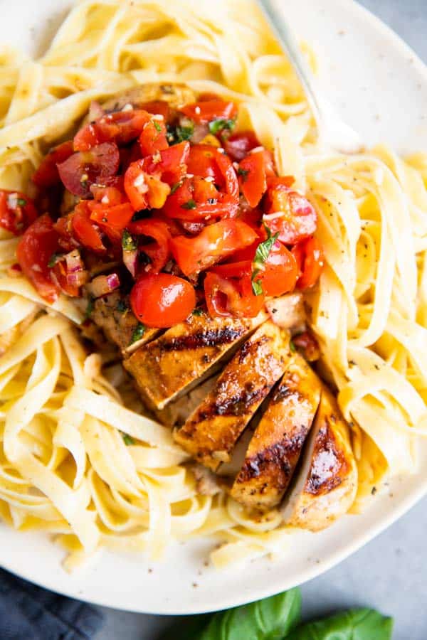 close up photo of grilled balsamic bruschetta chicken on top of fettuccine