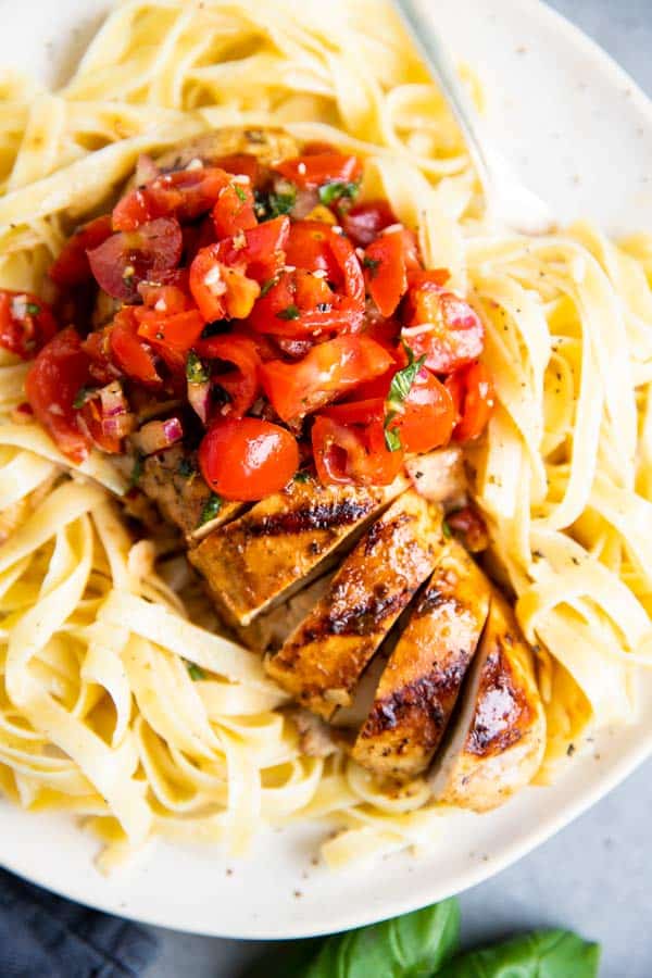 close up photo of grilled balsamic bruschetta chicken on top of fettuccine
