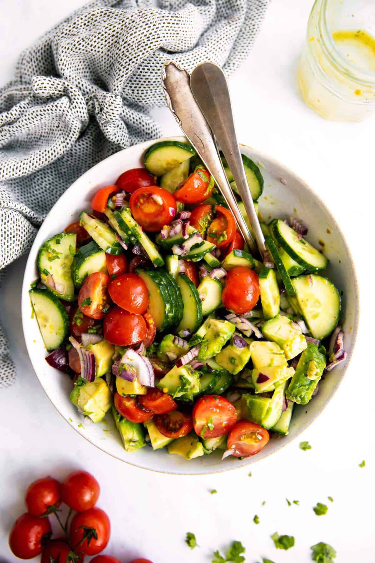 overhead view of white bowl with tomato cucumber avocado salad