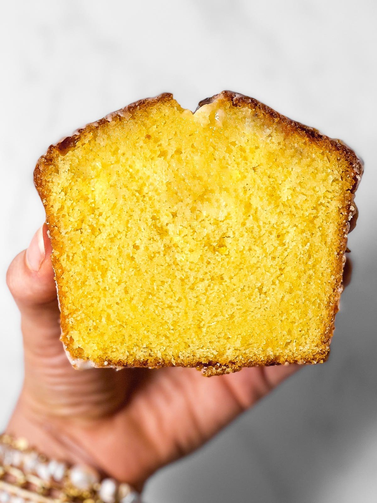 female hand holding slice of lemon pound cake