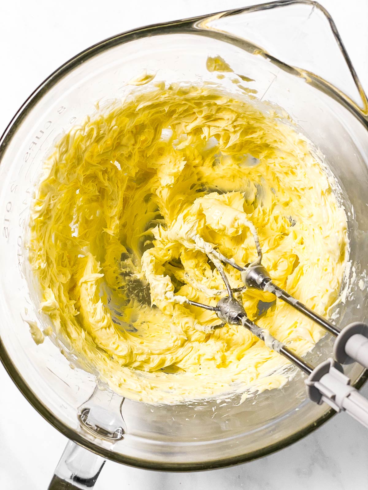 creamed butter in glass bowl with mixer beaters